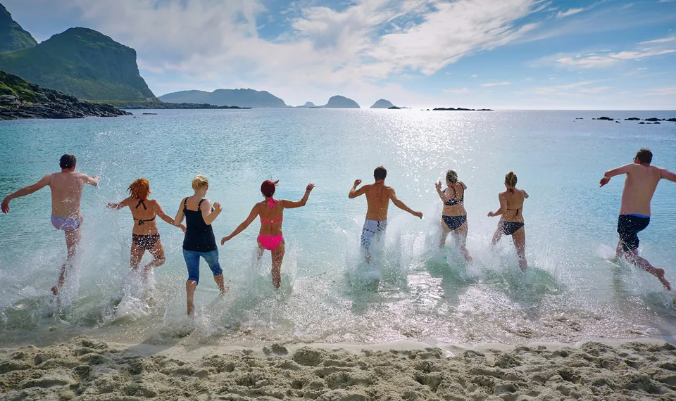 Grupo de amigos corriendo hacia el mar