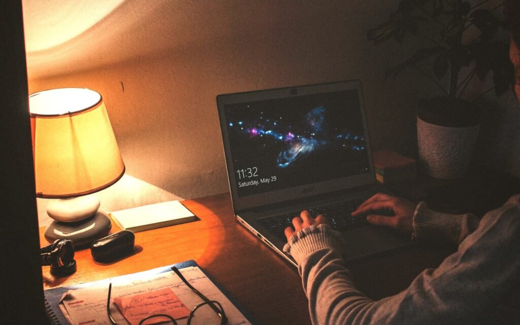 Persona trabajando con el portátil de noche junto a una lámpara cálida